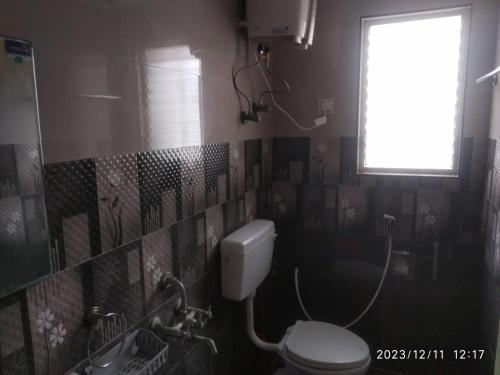 een badkamer met een toilet en een raam bij Royale Seaward Cozy Suite in Chennai