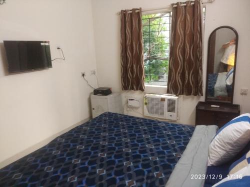 1 dormitorio con 1 cama, TV y ventana en Royale Seaward Cozy Suite, en Chennai