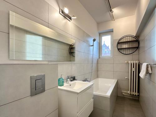 a white bathroom with a sink and a mirror at Apartament Willow in Gdańsk