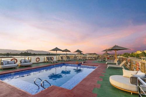 a pool with chairs and umbrellas on top of a hotel at Nile Cruise Every Monday 4 Nights from Luxor to Aswan in Luxor