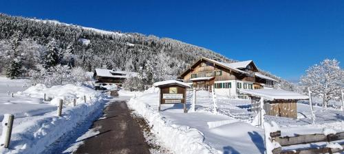 een met sneeuw bedekte hut met een bord ervoor bij Haflingerhof - Kematsried in Bad Hindelang