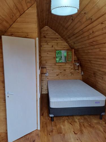 a bedroom with a bed in a wooden room at Hostel Chacra La Templanza in El Hoyo