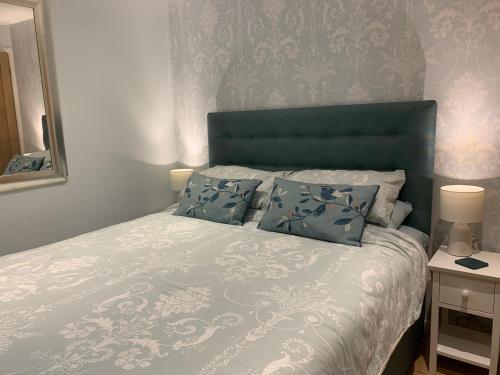 a bedroom with a bed with a blue headboard and a mirror at The Lady of the Lake Windermere in Windermere
