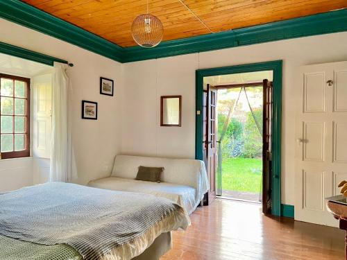 a bedroom with two beds and a door to a yard at Casa Via d'Agua in Fajã Grande in Faja Grande