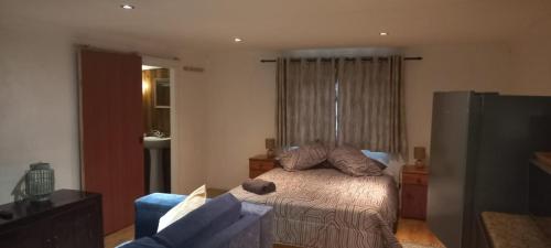 a bedroom with a bed and a couch and a television at Timber Ally Cabin in Umtentweni