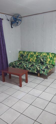 Raihei Location maison d'hôtes في بورا بورا: أريكة خضراء في غرفة مع طاولة قهوة