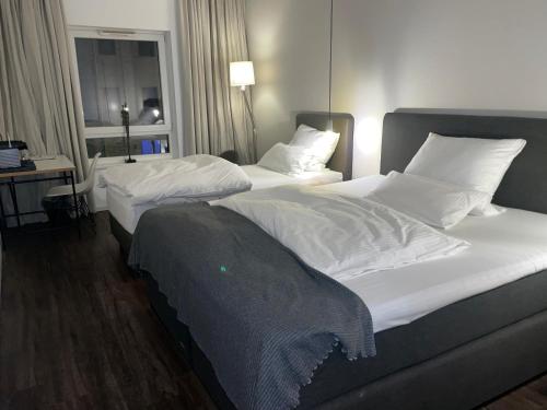 ein Hotelzimmer mit 2 Betten und einem Tisch mit einem Fenster in der Unterkunft Hotel Lindenhof in Erkelenz