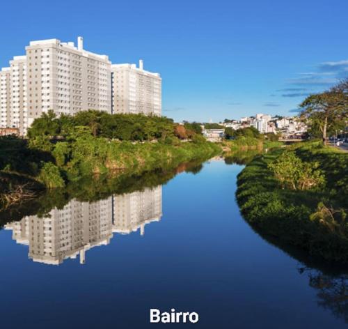 a river with buildings in the background with a reflection in the water at Apartamento 2 quartos completo com garagem in Juiz de Fora