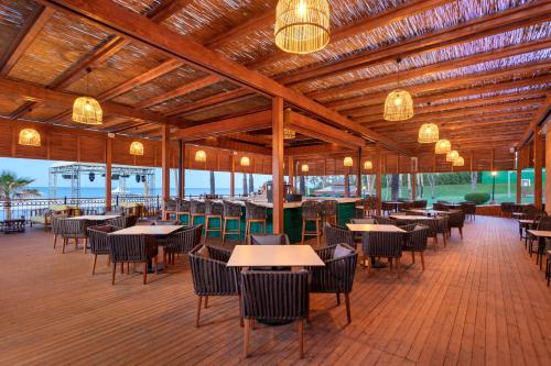 a restaurant with tables and chairs and chandeliers at Dobedan Beach Resort Comfort ''Ex Brand Alva Donna Beach Resort Comfort'' in Side