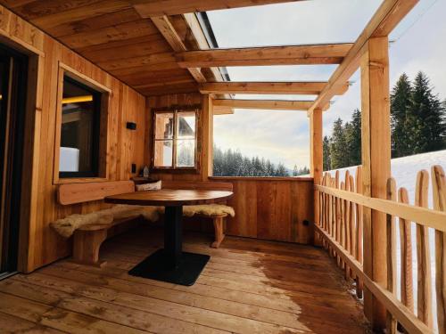 eine Holzterrasse mit einem Tisch und einem Fenster in der Unterkunft Finks Appartement in Going