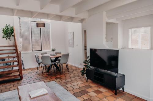 a living room with a television and a table with chairs at The Sage Cottage - Explore Bendigo CBD on foot! in Bendigo