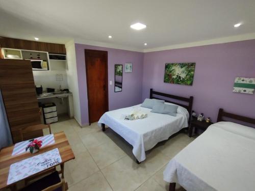 a bedroom with two beds and a kitchen in it at Marina Guest House in Búzios