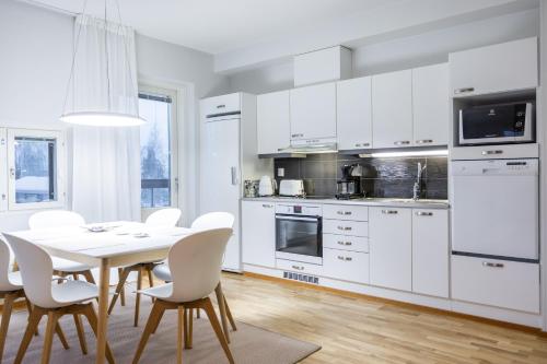 - une cuisine avec des placards blancs, une table et des chaises dans l'établissement Nordic Design Apartment City Center, à Rovaniemi