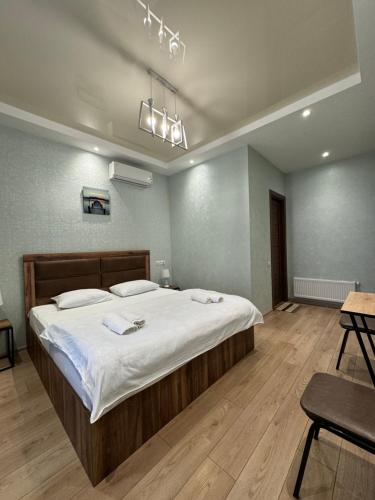 een slaapkamer met een groot bed met witte lakens bij Veranda L&G in Koetaisi