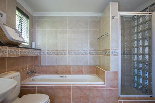 a bathroom with a tub and a toilet at Suikerbos Guesthouse in Cape Town