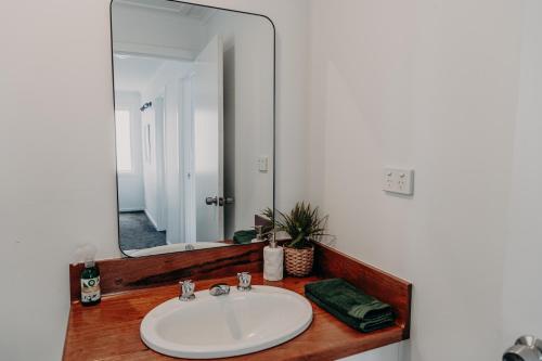 La salle de bains est pourvue d'un lavabo et d'un grand miroir. dans l'établissement The Sage Cottage - Explore Bendigo CBD on foot!, à Bendigo