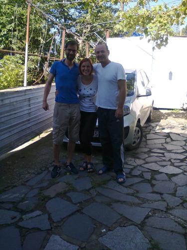two men and a woman standing next to a car at Giorgi's Homestay in Kutaisi