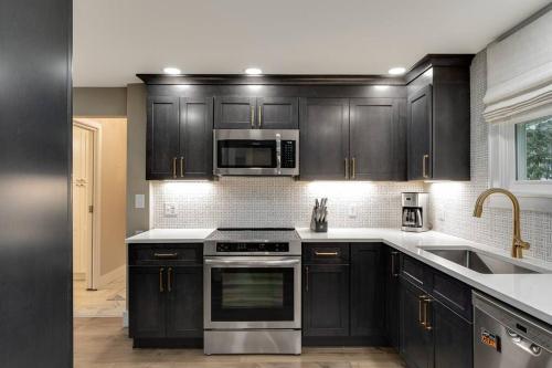 a kitchen with black cabinets and stainless steel appliances at Riverside Retreat! in West Lafayette