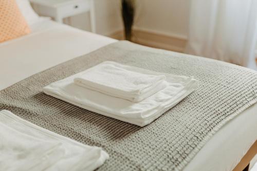 zwei weiße Handtücher auf dem Bett in der Unterkunft Belém Tejo - Jardim in Lissabon