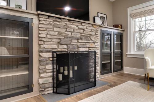 a stone fireplace in a living room with a tv above it at Riverside Retreat! in West Lafayette