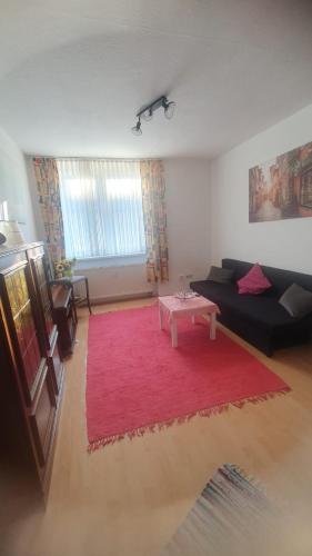 uma sala de estar com um sofá preto e um tapete vermelho em Apartment 8 Pirmasens em Pirmasens