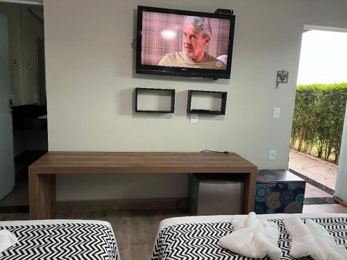 a room with a television on a wall with two beds at Cantinho da Alegria Suítes in Capitólio
