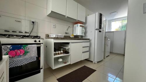 a white kitchen with a stove and a refrigerator at Apt. em Praia do Sul de Ilhéus in Ilhéus