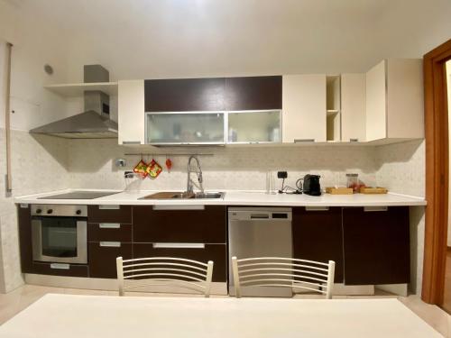 a kitchen with white cabinets and a sink and chairs at Gaslini and beaches two steps away in Genova