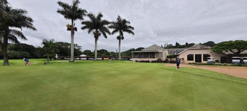 a group of people playing golf on a green with palm trees at Timber Ally Cabin in Umtentweni