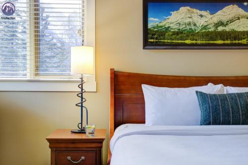 a bedroom with a bed and a lamp and a window at Chinook Manor in Canmore