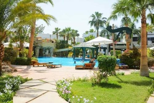 a swimming pool with palm trees and a resort at Shared room with the owner only at the Delta Hotel and Resort Sharm El Sheikh in Sharm El Sheikh