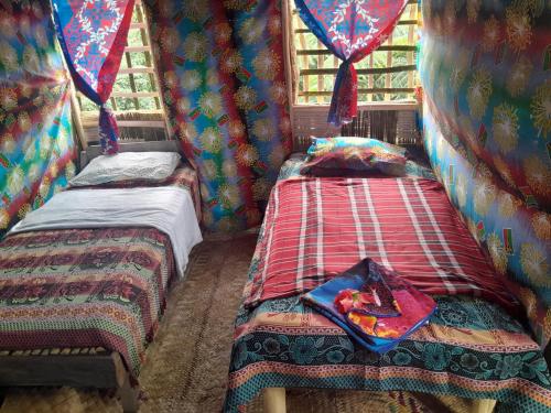 two twin beds in a room with curtains at Glowing Mountain view tree house in Loanengo