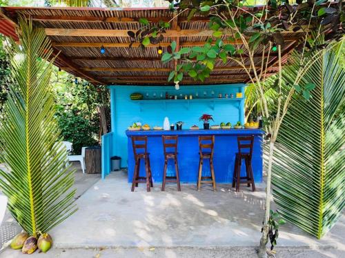 a blue bar with stools under a wooden pergola at Eco Hotel Las Palmeras in Isla Grande
