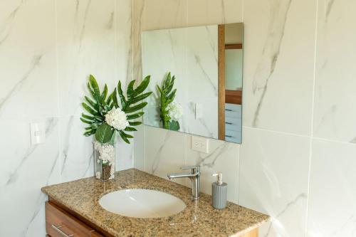 a bathroom with a sink and a vase with flowers at Villa Eliam in San Felipe de Puerto Plata