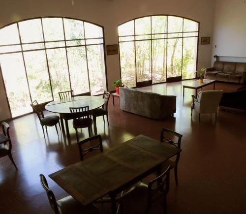 sala de estar con mesas, sillas y ventanas en Hostel Amarillo en San Ignacio