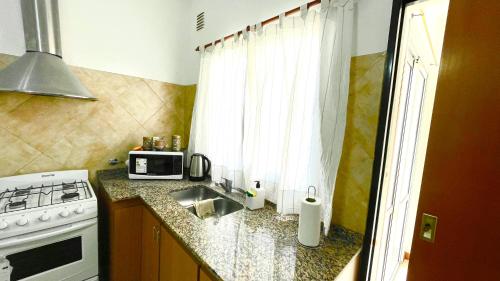 a kitchen with a sink and a stove and a microwave at Mimi’s Dream Luján 2 in Luján