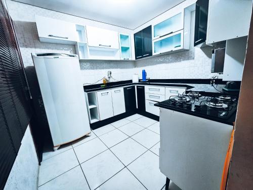 eine Küche mit weißen Geräten und schwarzen und weißen Schränken in der Unterkunft Casa para Hospedar in Fazenda Rio Grande