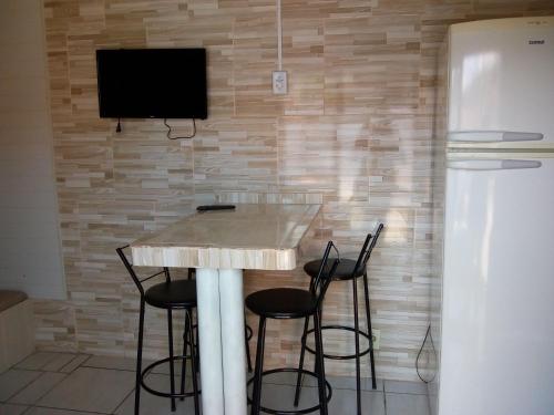 cocina con mesa con sillas y TV en la pared en AP praia Itaguaçu São Chico, en São Francisco do Sul