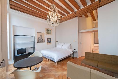 um quarto com uma cama branca e um lustre em Pavillon Marais em Paris