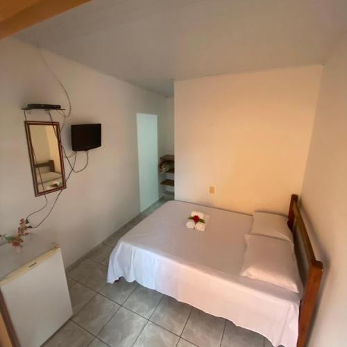a bedroom with a white bed with flowers on it at Pousada & Kitnet Nascer do Sol in Ilha de Boipeba