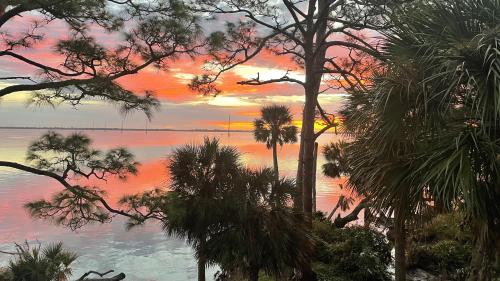einen Sonnenuntergang über einem Wasserkörper mit Palmen in der Unterkunft Florida Space Coast Waterfront Retreat in Cocoa