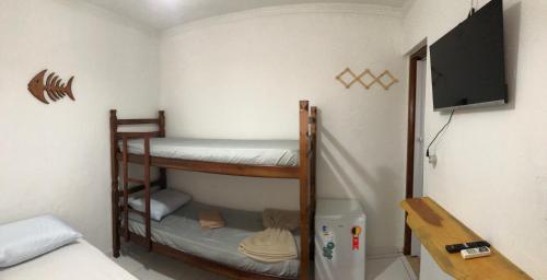 a room with two bunk beds and a flat screen tv at Pousada Beira-mar I in Bertioga