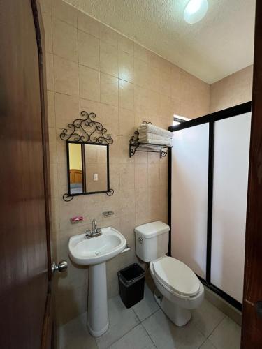 Un baño con inodoro, lavabo y espejo. en Hotel La Capilla Bernal, en Bernal