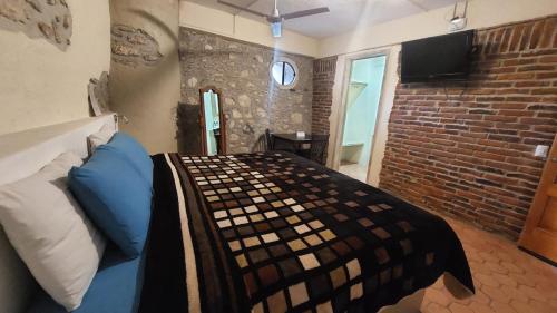 a bedroom with a bed and a brick wall at Hotel 19 de Enero Centro in Bernal