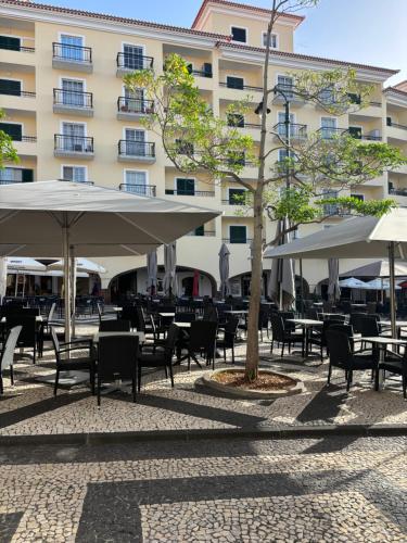 un patio con tavoli e ombrelloni di fronte a un edificio di Cc39 -Q1 a Funchal