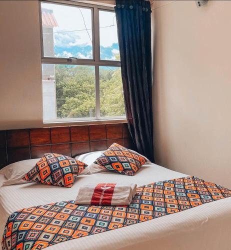 a bed with two pillows in front of a window at Hotel Tierra Santa in Santa Fe de Antioquia