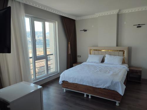 a bedroom with a bed and a large window at Hasankeyf Hasbahçe Otel in Hasankeyif