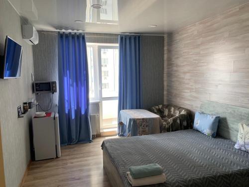 een slaapkamer met een bed en een raam met blauwe gordijnen bij ObolonSky in Kiev