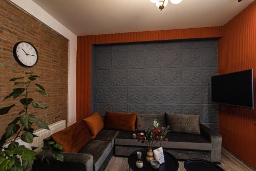a living room with a couch and a clock on a wall at Nice and cosy villa in the heart of the city in Tbilisi City