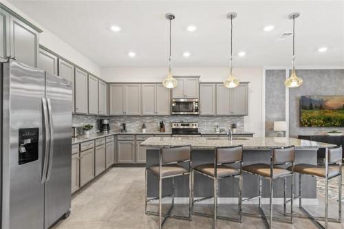 a kitchen with a stainless steel refrigerator and bar stools at 9 Bed Theatre Rm Stunner in Windsor Island in Davenport